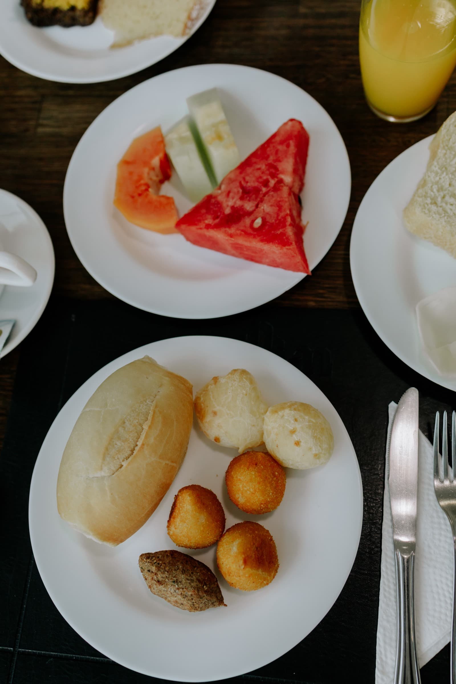 Prato de frutas e pão de queijo servidos à mesa do café da manhã