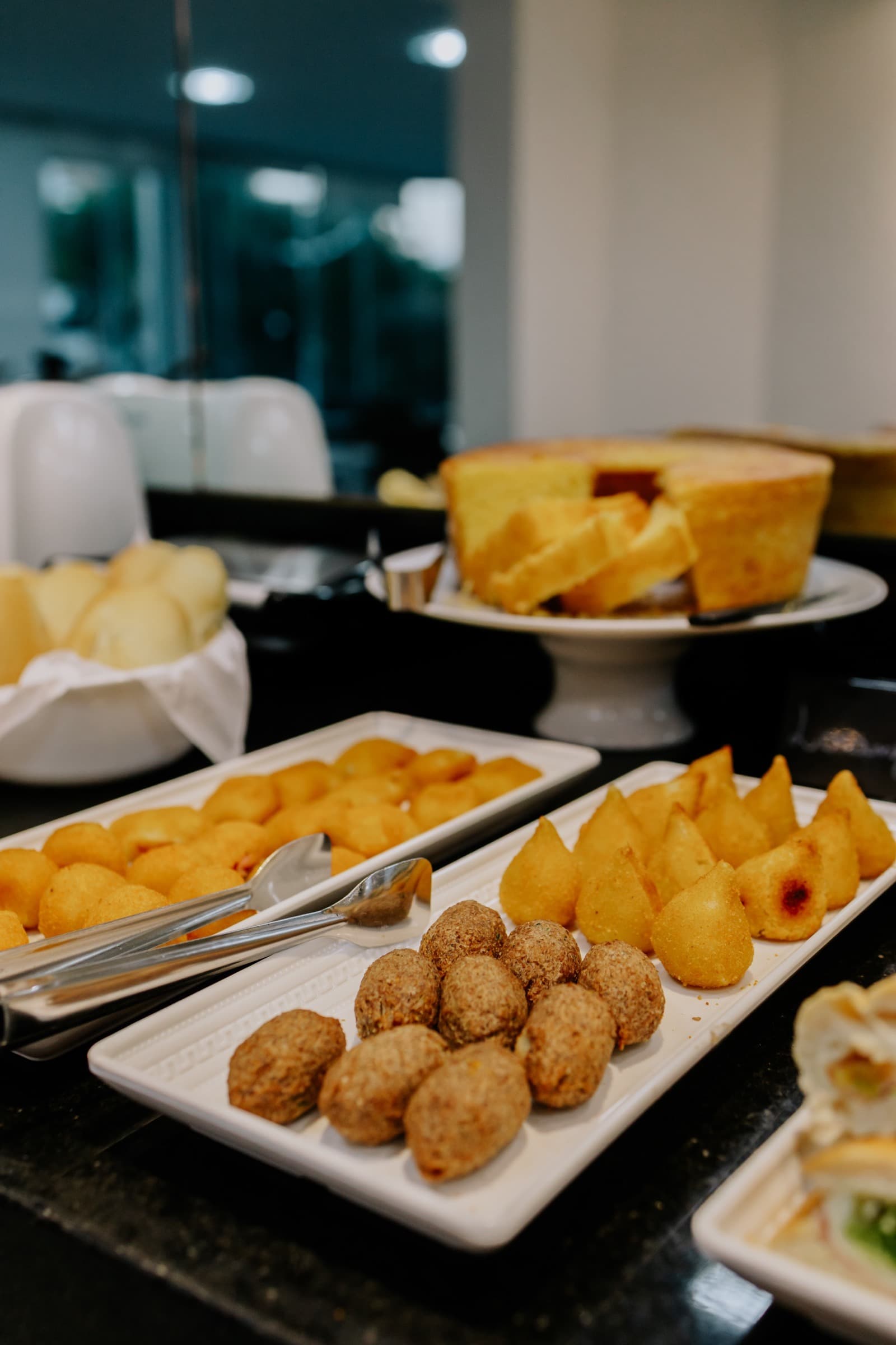 Coxinhas, kibes e bolo servidos no buffet do café da manhã