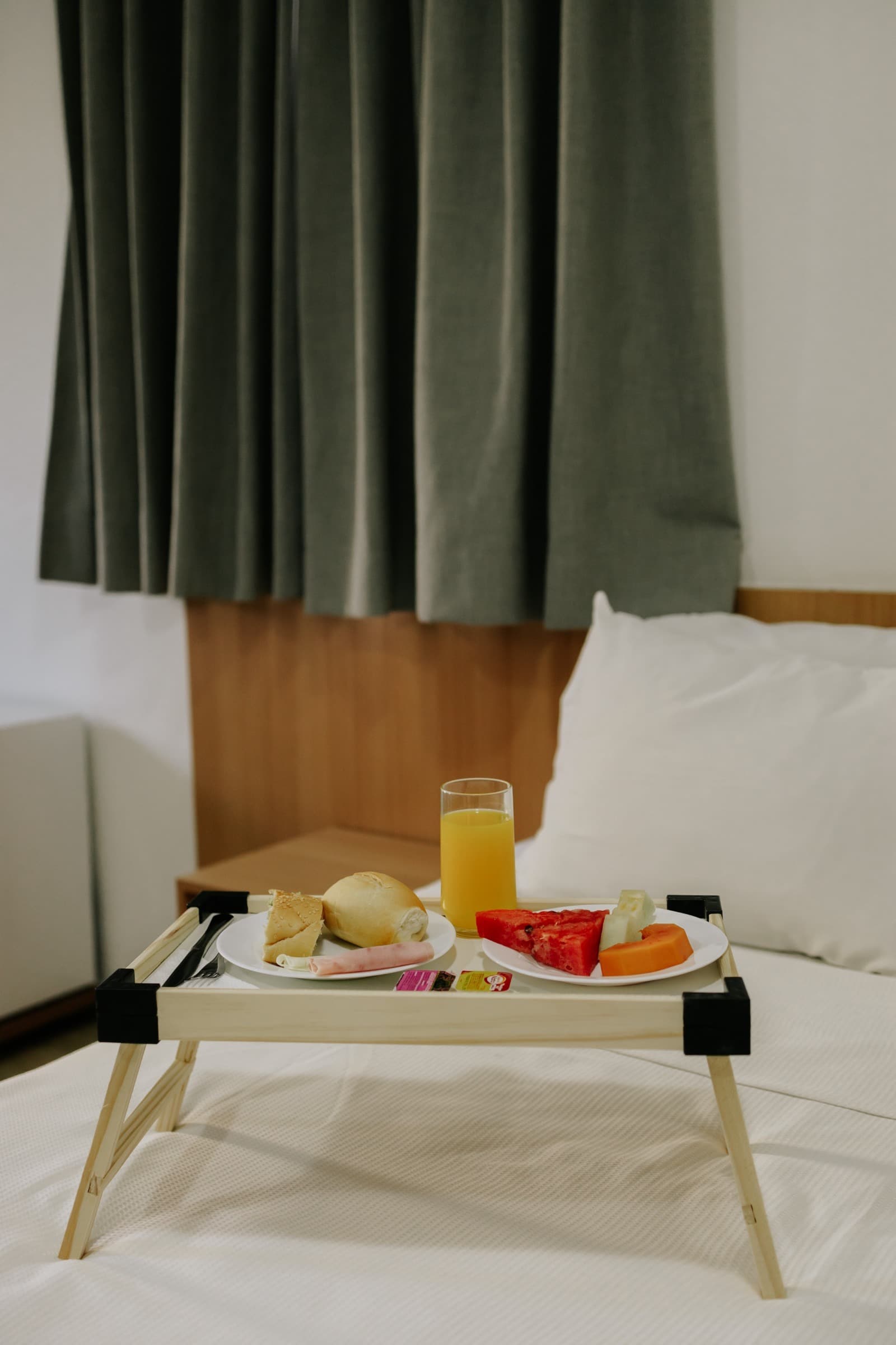 Bandeja de café da manhã com suco, pão e frutas, servida no quarto